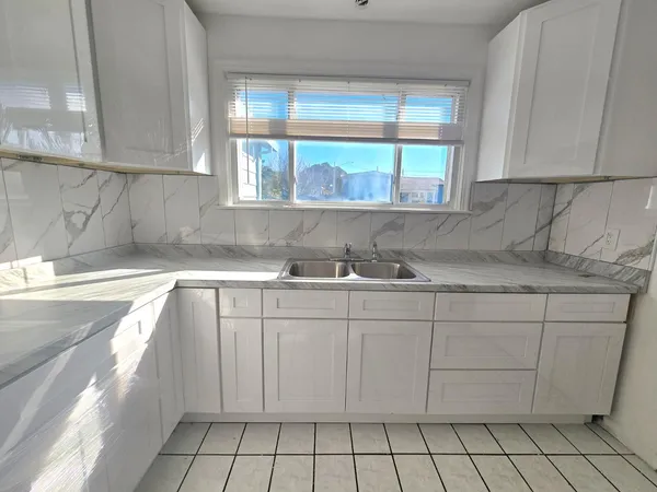 a kitchen with granite countertop white cabinets and sink