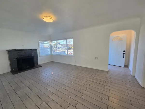 an empty room with windows and fireplace