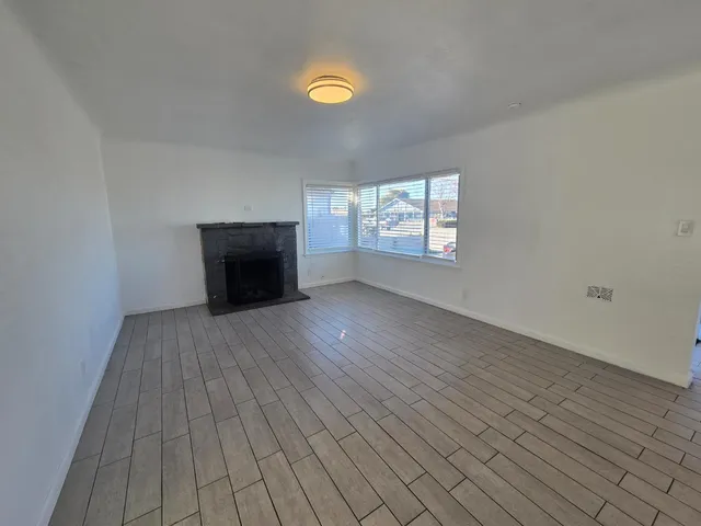 an empty room with windows and fireplace