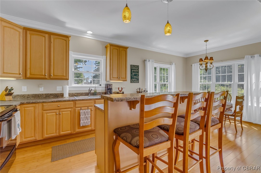 189 Virginia Road Reedville, VA 22539 - Photo 11 of 46 Kitchen with range with electric stovetop, a sink, healthy amount of natural light, a breakfast bar area, and crown molding