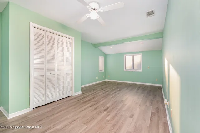 an empty room with wooden floor closet and windows