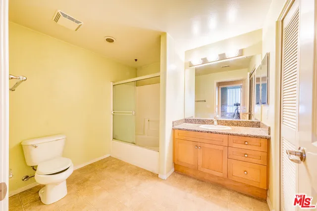 a bathroom with a granite countertop sink mirror vanity and toilet