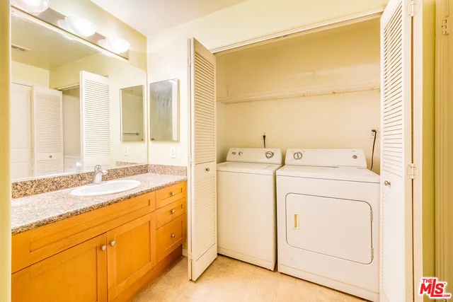 a view of washer and dryer with bathroom in the background