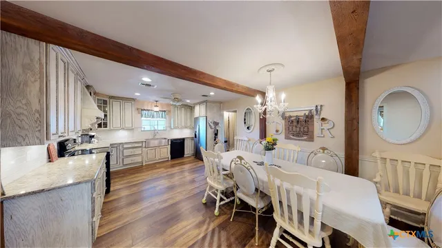a view of a dining room and livingroom with furniture wooden floor a chandelier