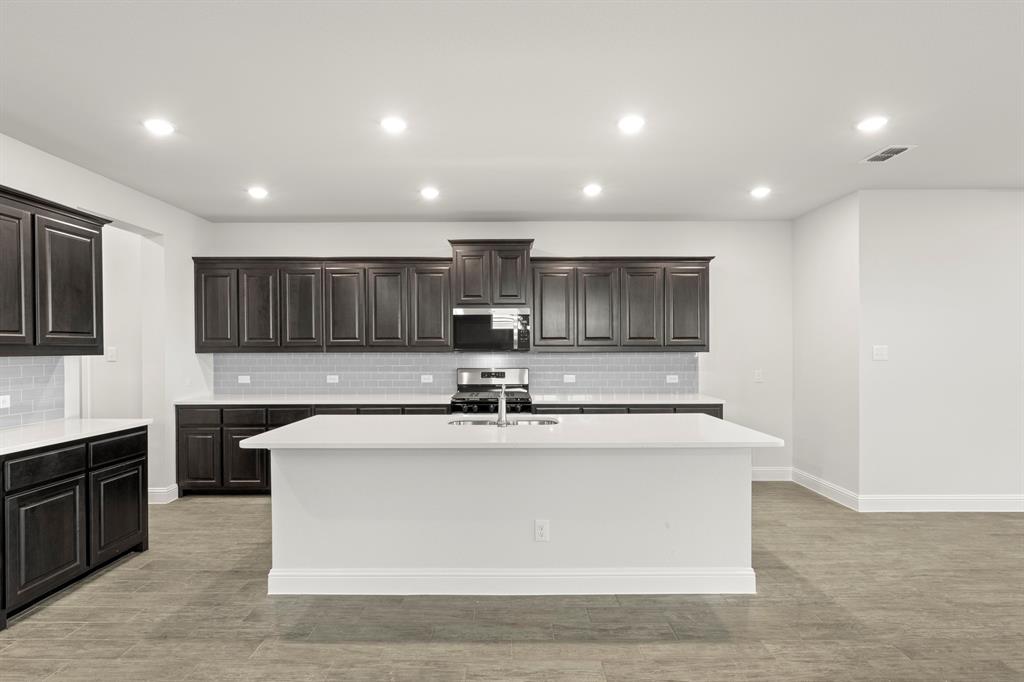 125 Meadow Road Balch Springs, TX 75181 - Photo 3 of 27 a view of a kitchen with kitchen island a sink wooden floor and counter top space