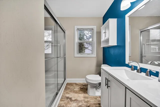 an empty room with wooden floor chandelier fan and windows