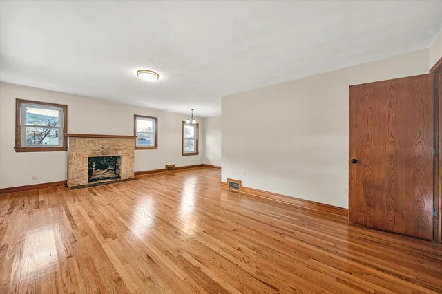 an empty room with wooden floor and fireplace