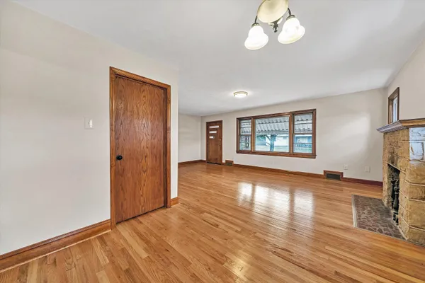 an empty room with wooden floor chandelier and windows