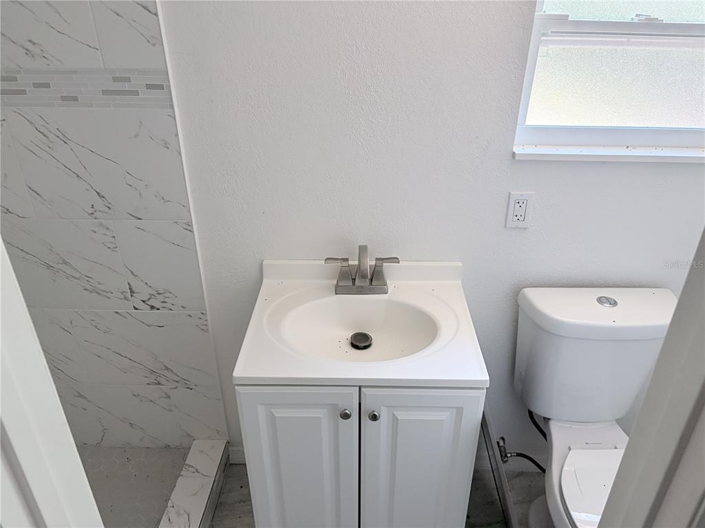 3818 Moog Road Holiday, FL 34691 - Photo 17 of 19 a bathroom with a sink a toilet and a mirror