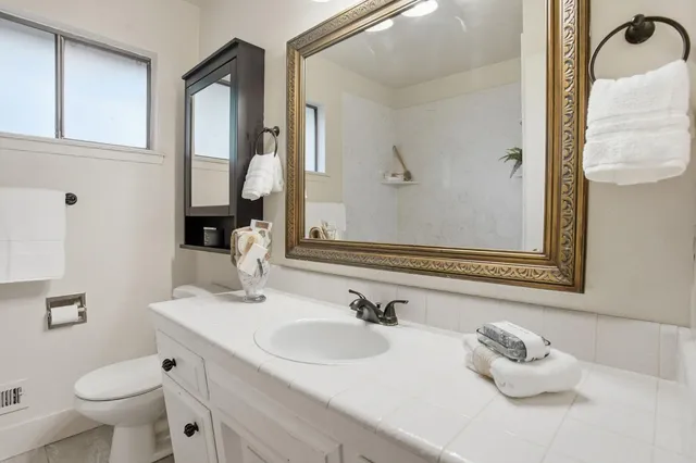 a bathroom with a sink vanity granite and toilet