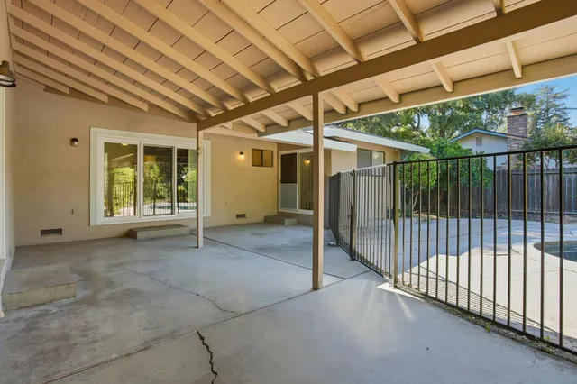 a view of backyard with large window and wooden fence