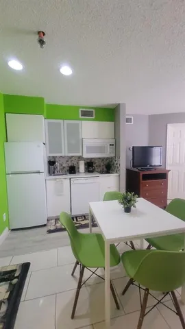 a kitchen with a dining table chairs and refrigerator