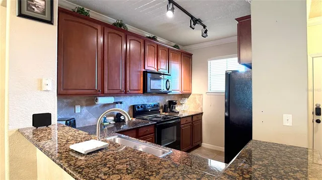 a kitchen with stainless steel appliances granite countertop a sink stove and refrigerator