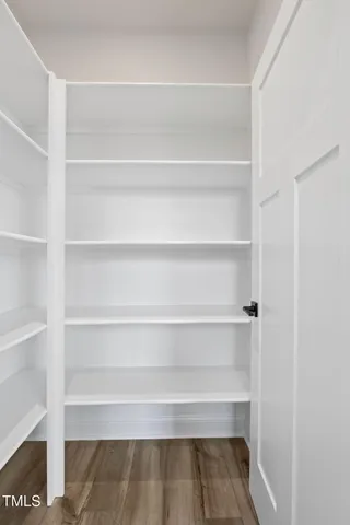 a kitchen with stainless steel appliances kitchen island granite countertop a stove a sink a refrigerator and white cabinets with wooden floor