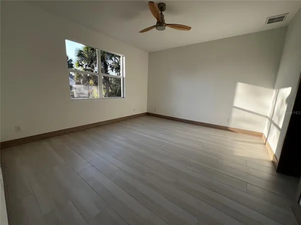 a view of an empty room with wooden floor and a window