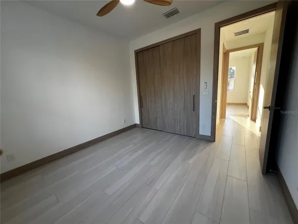 an empty room with wooden floor and a ceiling fan
