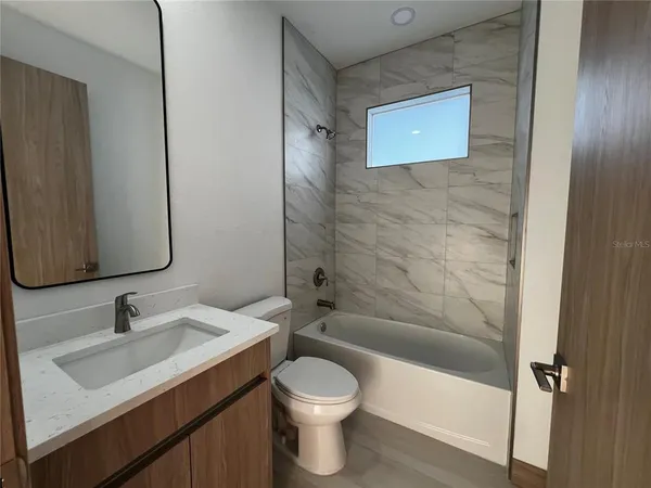 a bathroom with a toilet sink vanity tub and shower