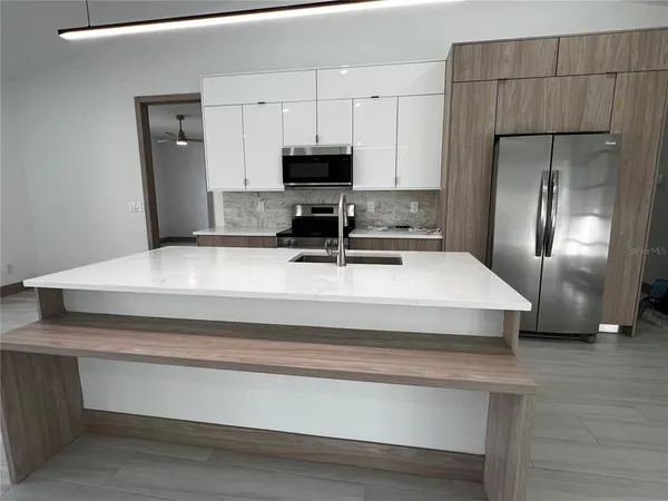 a kitchen with kitchen island a counter top space a refrigerator and cabinets