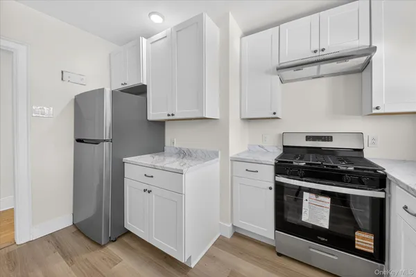 a kitchen with granite countertop white cabinets and stainless steel appliances