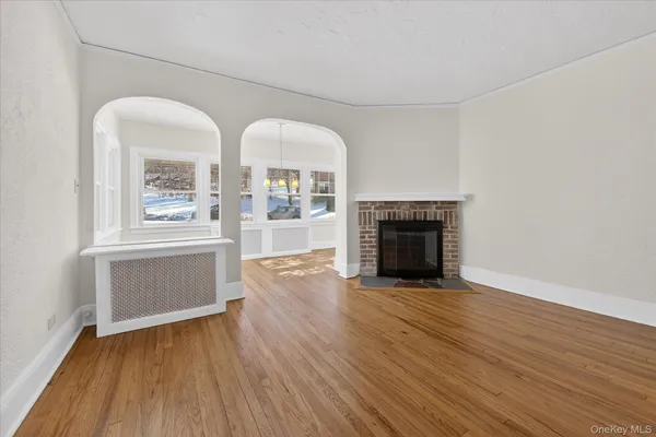 an empty room with wooden floor fireplace and windows
