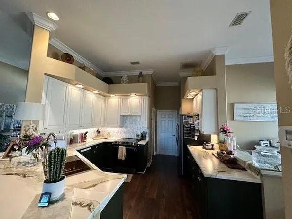 a room with stainless steel appliances kitchen island granite countertop a sink dishwasher and a dining table with wooden floor