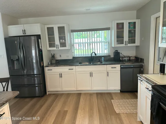 a kitchen with granite countertop a refrigerator sink and cabinets