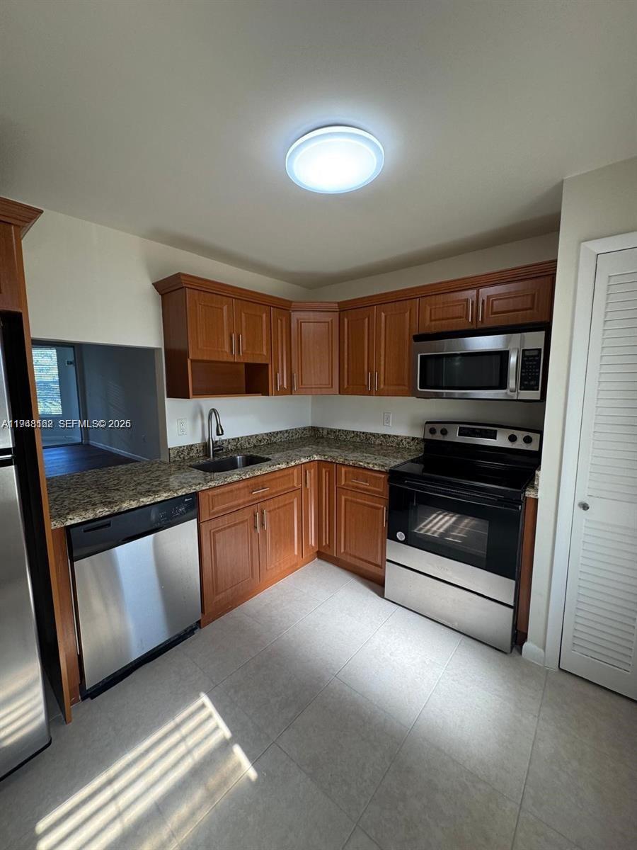 1201 Northeast 191st Street, Unit G313 Miami, FL 33179 - Photo 3 of 15 a kitchen with sink a microwave and cabinets