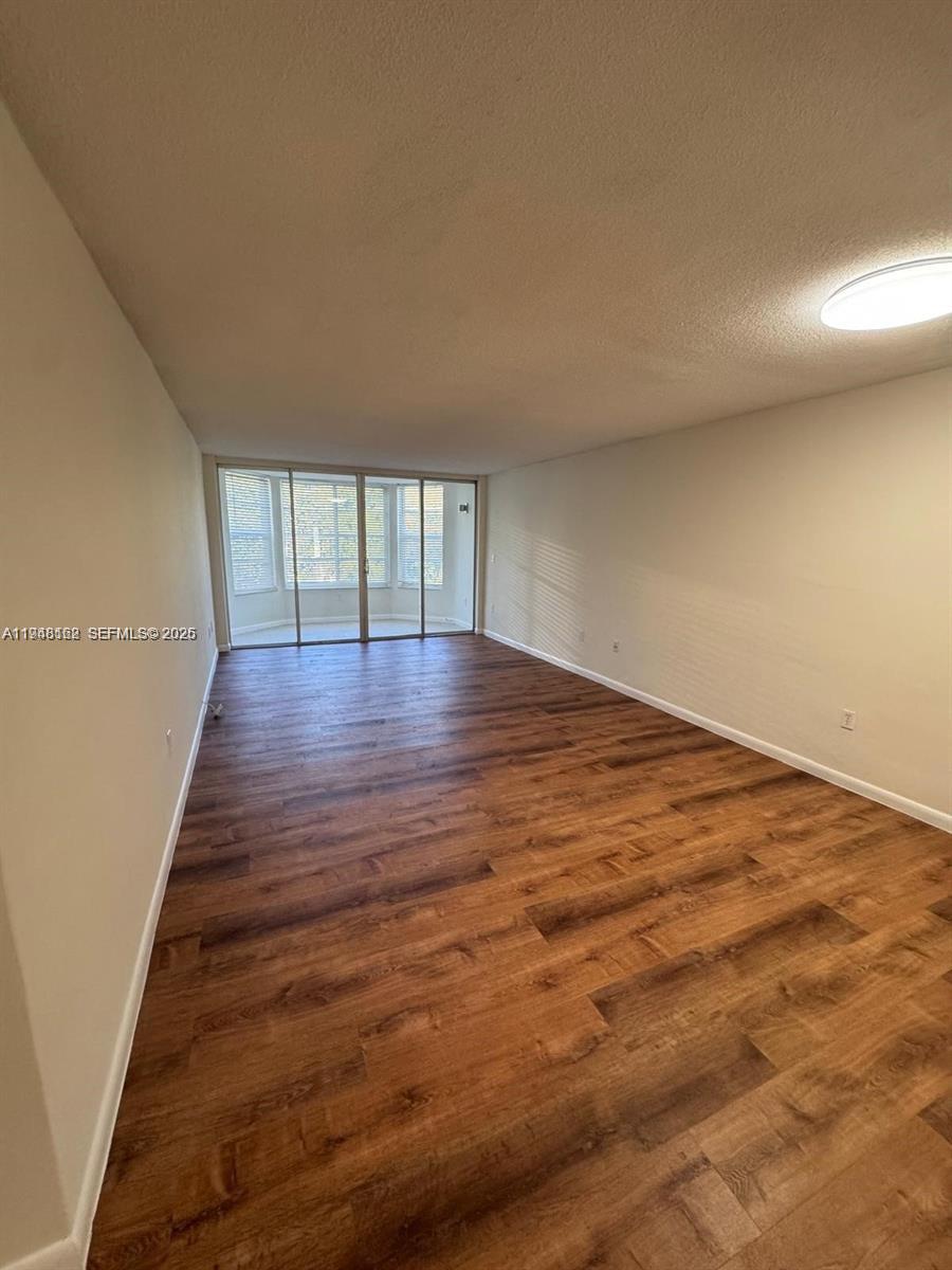 1201 Northeast 191st Street, Unit G313 Miami, FL 33179 - Photo 6 of 15 a view of an empty room with wooden floor