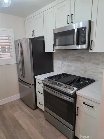 a kitchen with stainless steel appliances white cabinets a stove a microwave and a refrigerator