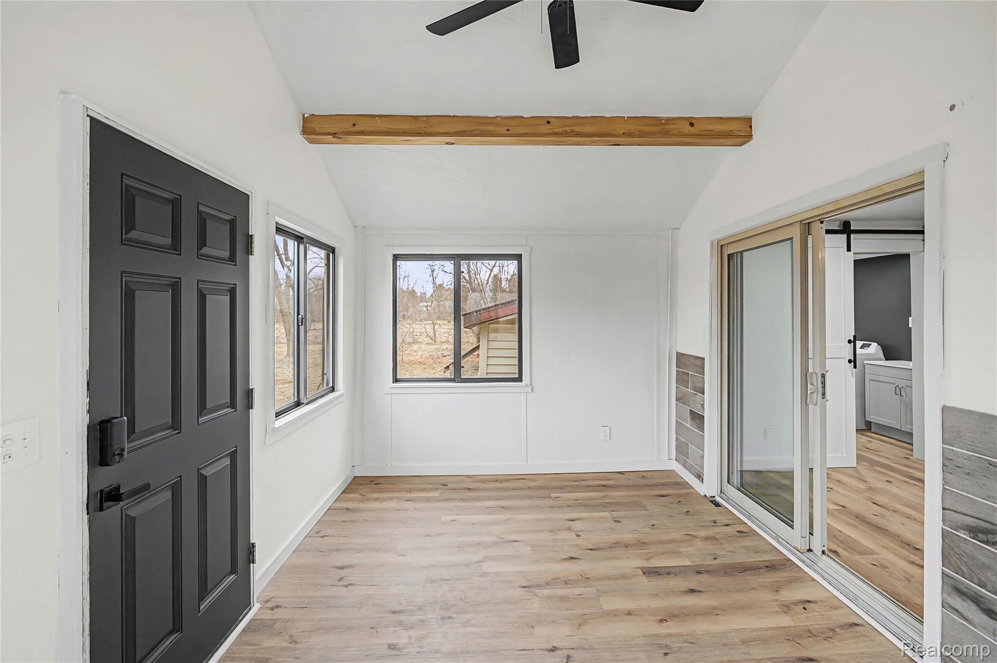14308 North Belsay Road Millington, MI 48746 - Photo 21 of 51 Unfurnished bedroom featuring vaulted ceiling with beams, light wood-style flooring, a ceiling fan, a barn door, and a closet