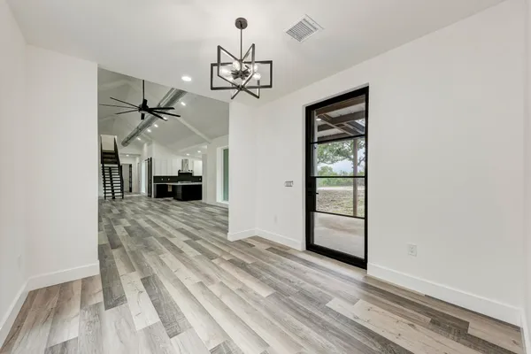 en empty room with wooden floor fireplace and window