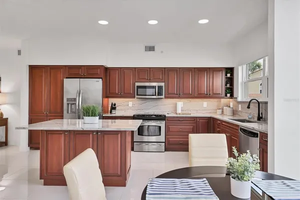 a kitchen with stainless steel appliances granite countertop a refrigerator a sink dishwasher a stove with wooden cabinets and floor