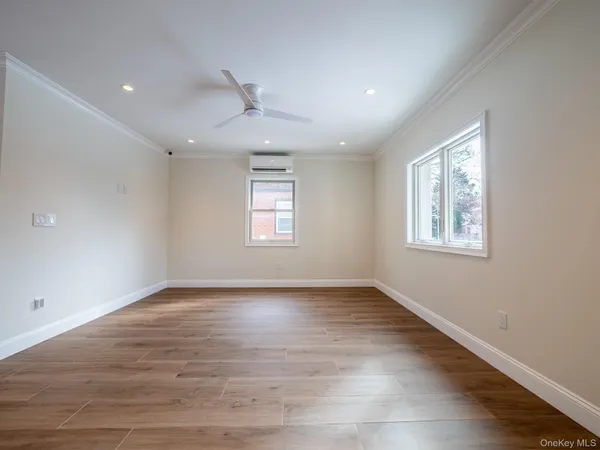 an empty room with wooden floor chandelier and windows