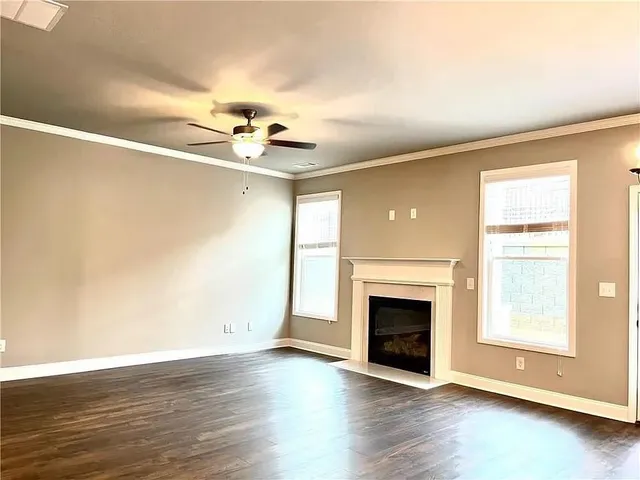 an empty room with windows fireplace and a wooden floor