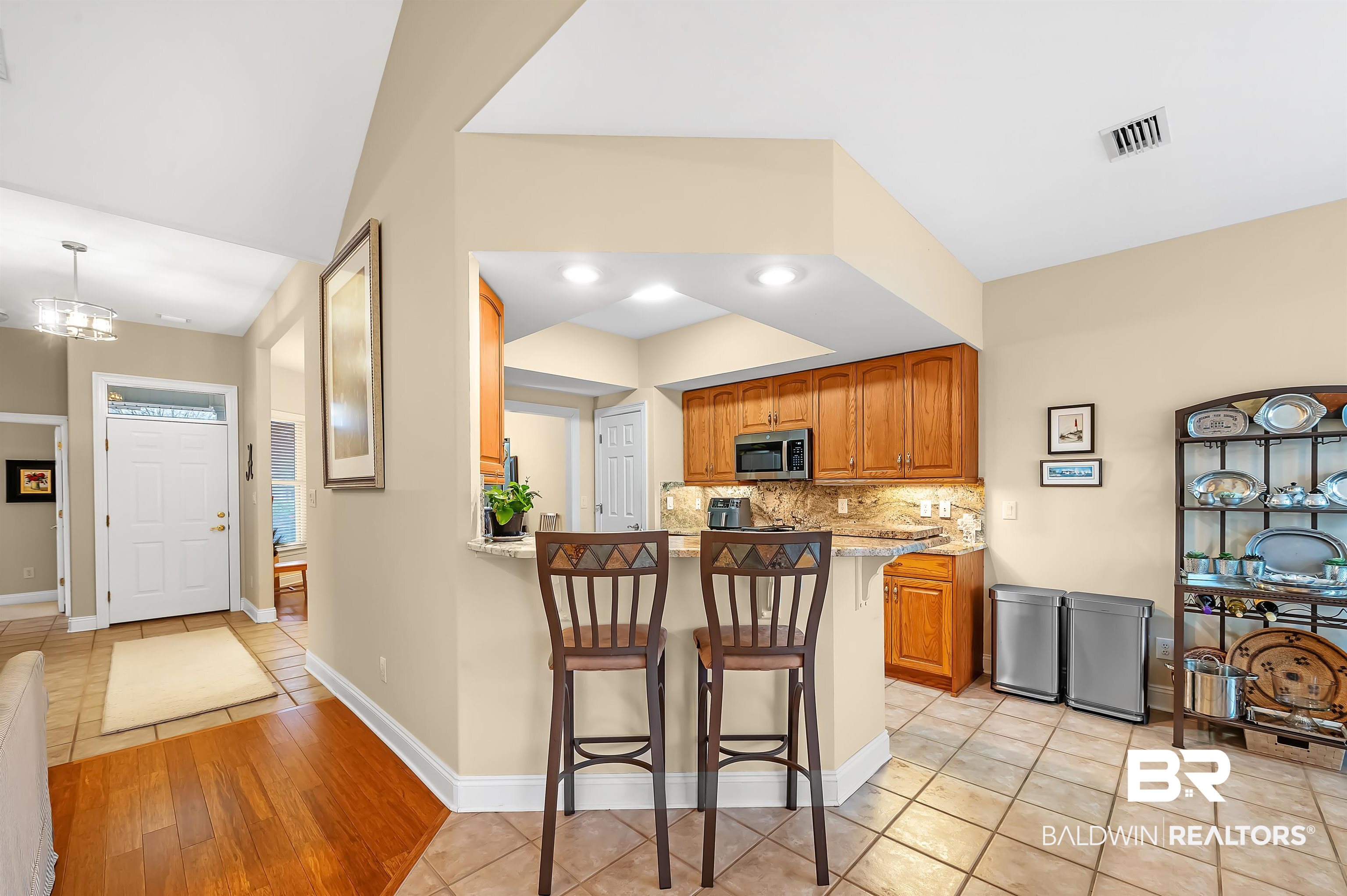 22726 Inverness Way Foley, AL 36535 - Photo 22 of 51 Kitchen featuring a kitchen bar, kitchen peninsula, light stone counters, and light tile patterned floors