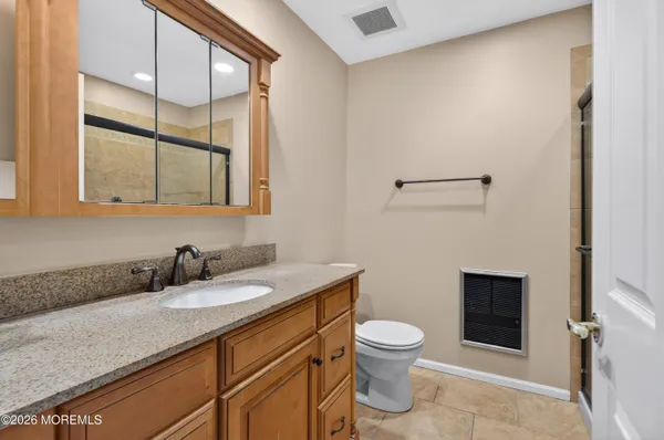 a bathroom with a granite countertop sink a toilet and a mirror