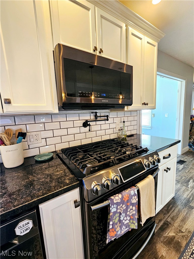 20037 Mosher Road Wellington, OH 44090 - Photo 6 of 27 Kitchen with white cabinets, tasteful backsplash, dark hardwood / wood-style flooring, dark stone countertops, and range with a pot filler above