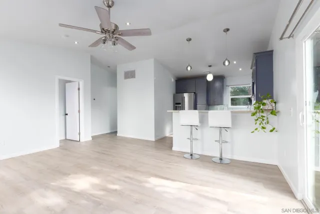 a view of a room with a ceiling fan and hardwood floor