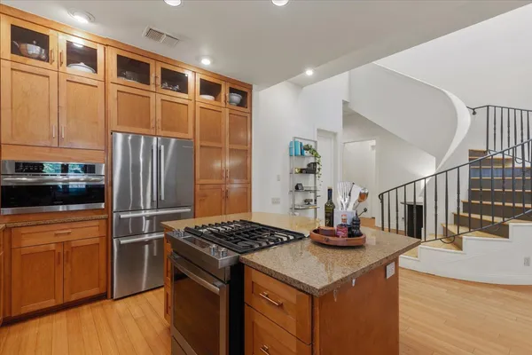 a kitchen with granite countertop a table chairs stove refrigerator and wooden cabinets