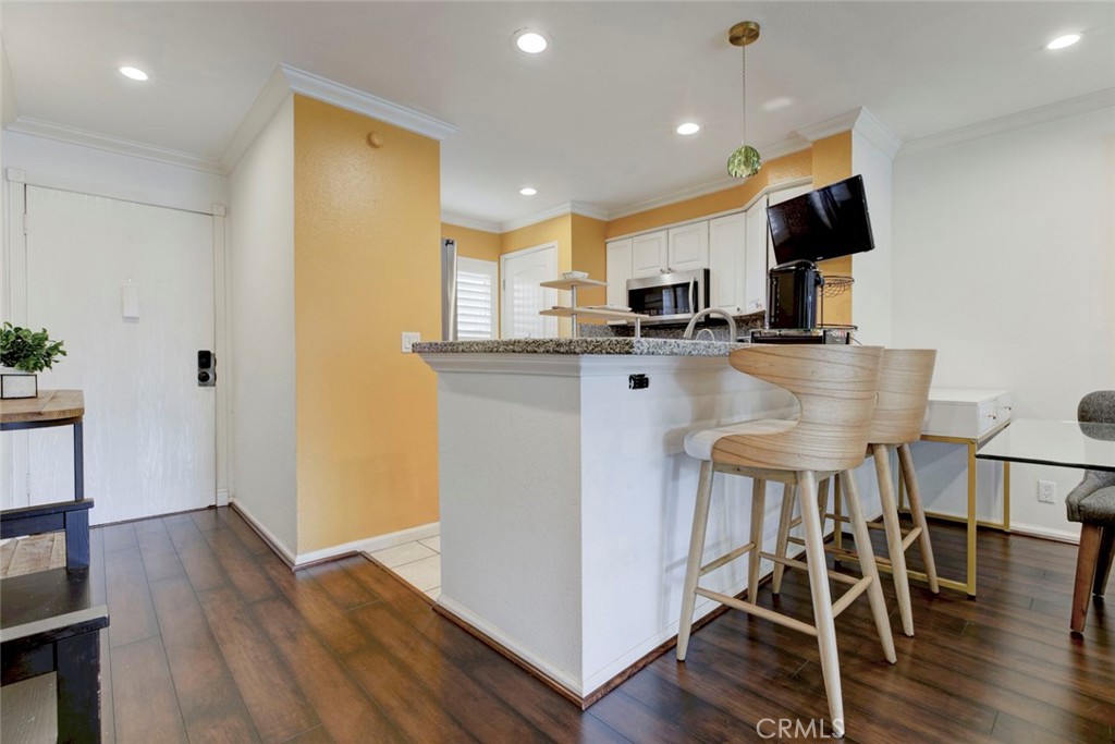 2940 North Verdugo Road, Unit 305 Glendale, CA 91208 - Photo 12 of 26 a kitchen with stainless steel appliances a microwave a stove a refrigerator a sink a dining table and chairs with wooden floor