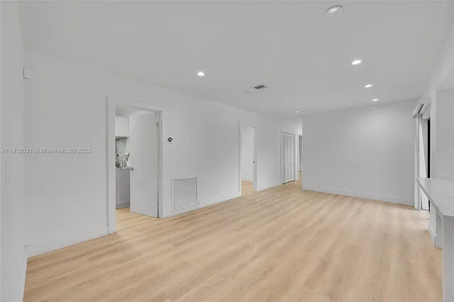 a view of an empty room with wooden floor and a ceiling fan