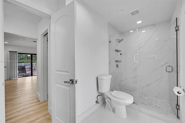 a large white kitchen with stainless steel appliances kitchen island granite countertop a refrigerator and a stove top oven