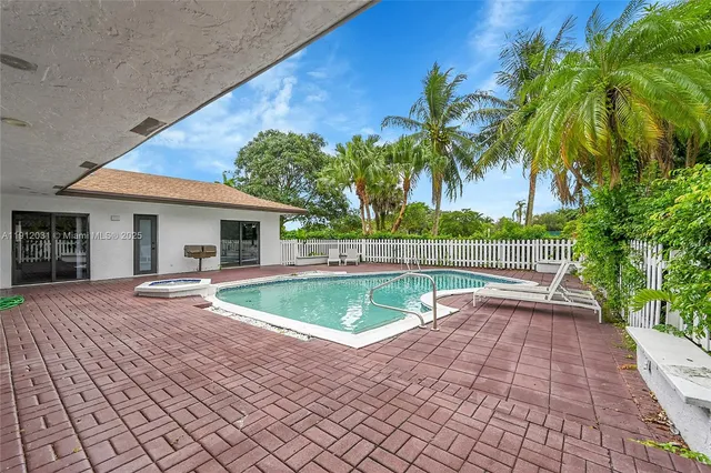 an aerial view of a residential houses with outdoor space and trees all around