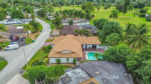 an aerial view of residential houses with outdoor space and trees