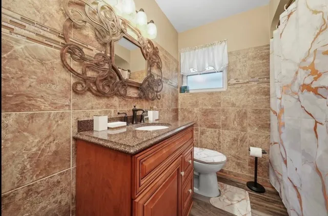 a bathroom with a granite countertop toilet sink and mirror