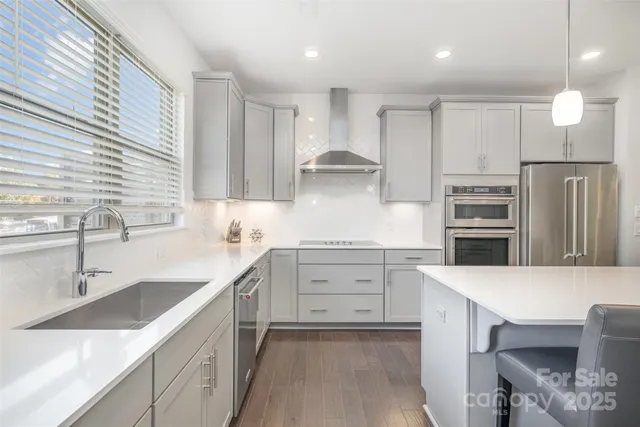 a large kitchen with a counter space a sink appliances and living room view