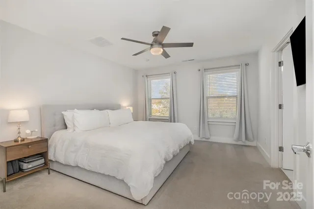 a bedroom with a bed flat screen tv closet and a window