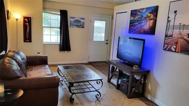 a living room with furniture a flat screen tv and a window