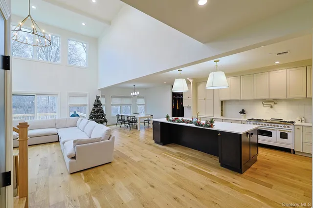 a large white kitchen with kitchen island a island a sink a stove and a wooden floors