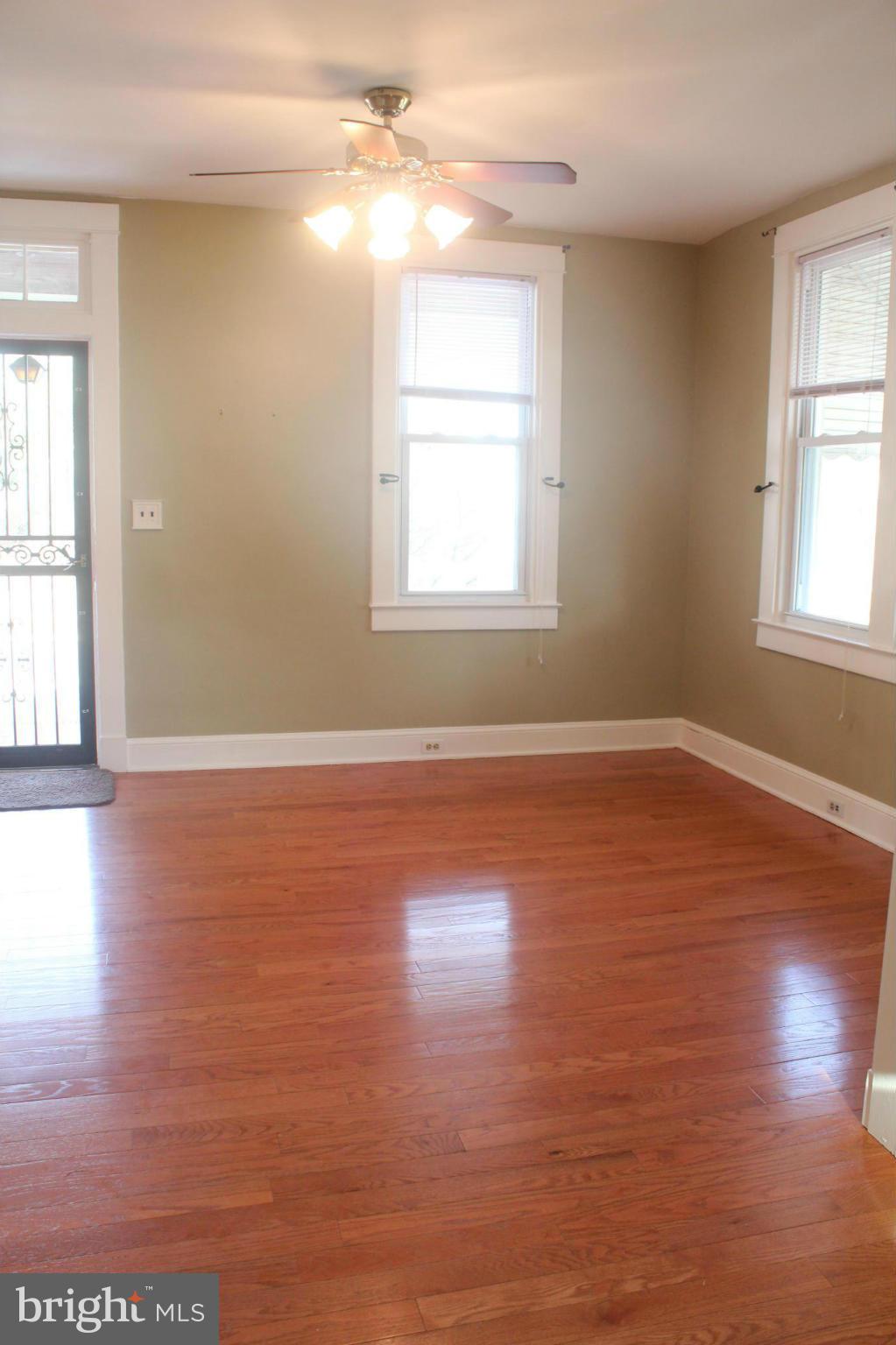 650 North Bend Road Baltimore, MD 21229 - Photo 5 of 22 an empty room with wooden floor and windows with curtains